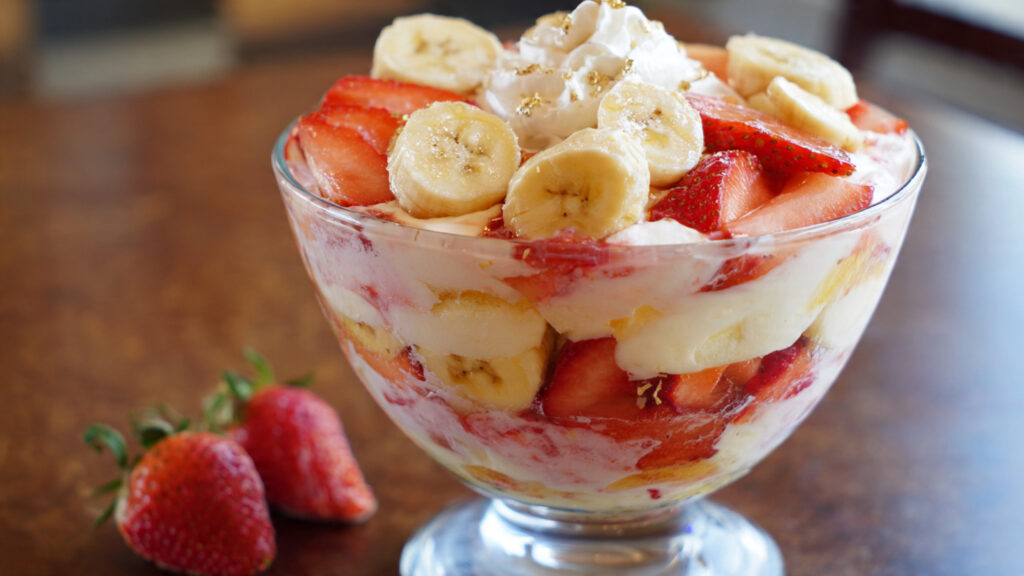 A perfect slice of no-bake strawberry banana pudding lasagna on a plate, showcasing the creamy layers and a golden cookie crust.